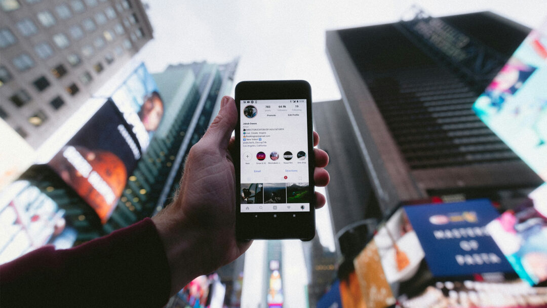 Sociala medier från avsändare till användare (illustreras med en person som håller upp en mobiltelefon mot stadshimlen)
