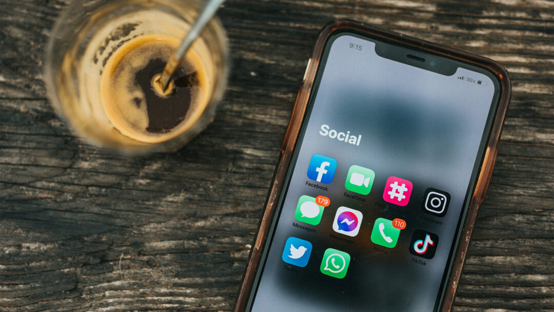 Facebook (illustrerat av en mobiltelefon på ett bord, med sociala medier-appar)